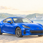 穏やかな港に停まるWRブルーのBRZと、海を進む白いフェリーのイラスト。